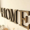 A row of vintage wooden alphabet letters spelling HOME mounted on a white wall.