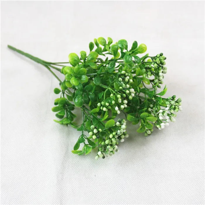 Green artificial fern and leaf sprigs with small white flowers for decoration