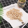 A pile of natural wooden clips in various shades of blue and beige scattered on a white paper next to a potted plant.