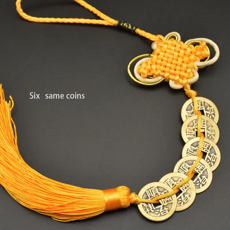A necklace featuring six copper coins tied together with a handwoven knot and a yellow cord.