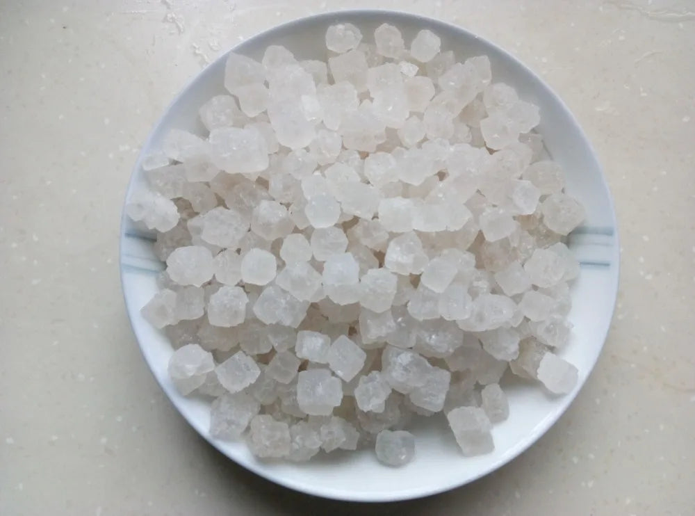 A pile of white natural unrefined sea salt crystals on a white plate.