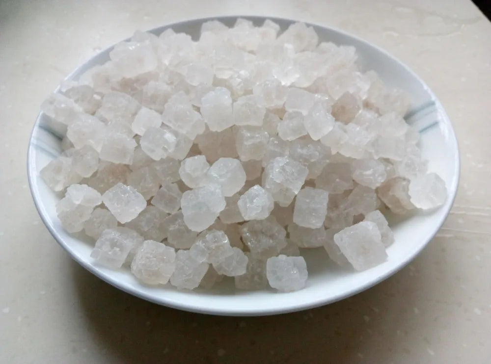 A pile of white natural unrefined sea salt crystals in a white dish.