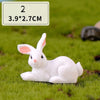 A white miniature rabbit figurine lying on green grass.