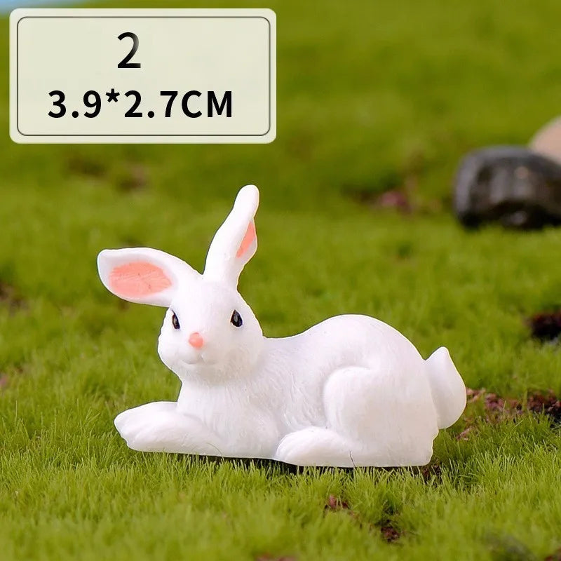 A white miniature rabbit figurine lying on green grass.
