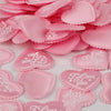 Pink heart-shaped sponge confetti scattered on a white surface for weddings and celebrations