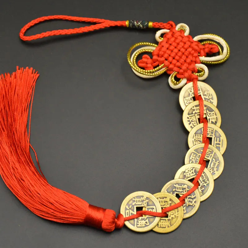 A necklace featuring an I Ching copper coin charm with a handwoven knot and red cord.