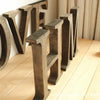 A row of vintage wooden alphabet letters spelling LOVE displayed on a light wooden floor.