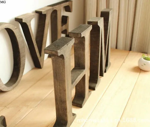 A row of vintage wooden alphabet letters spelling LOVE displayed on a light wooden floor.