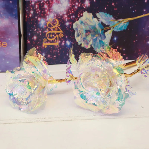 A bouquet of artificial roses with iridescent, multicolored petals and gold foil stems against a dark background.