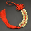 A round necklace made of copper coins and a red silk tassel, used as an I Ching Feng Shui charm.