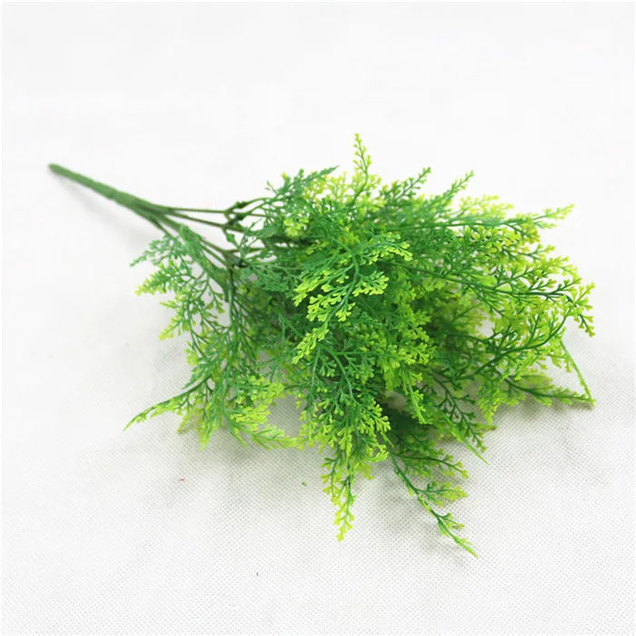 A sprig of bright green artificial fern leaves and fronds for decoration.