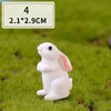 A white miniature rabbit figurine sitting on green grass.
