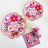 A pink floral disposable tableware set featuring pink and red flowers on plates and a cup.