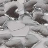 Silver heart-shaped sponge confetti pieces scattered on a white surface