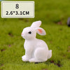 A white miniature rabbit figurine sitting on green grass.