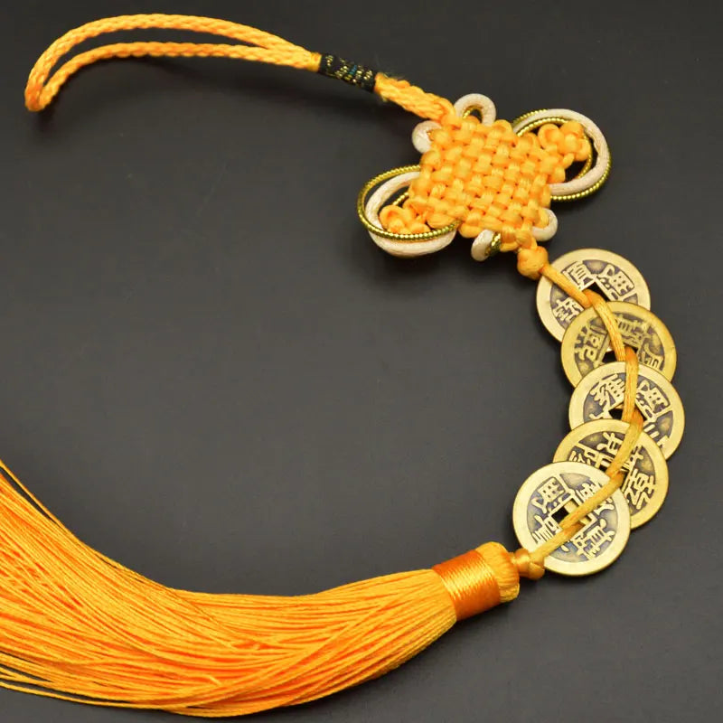 An I Ching copper coin feng shui charm with a handwoven knot and orange silk thread.