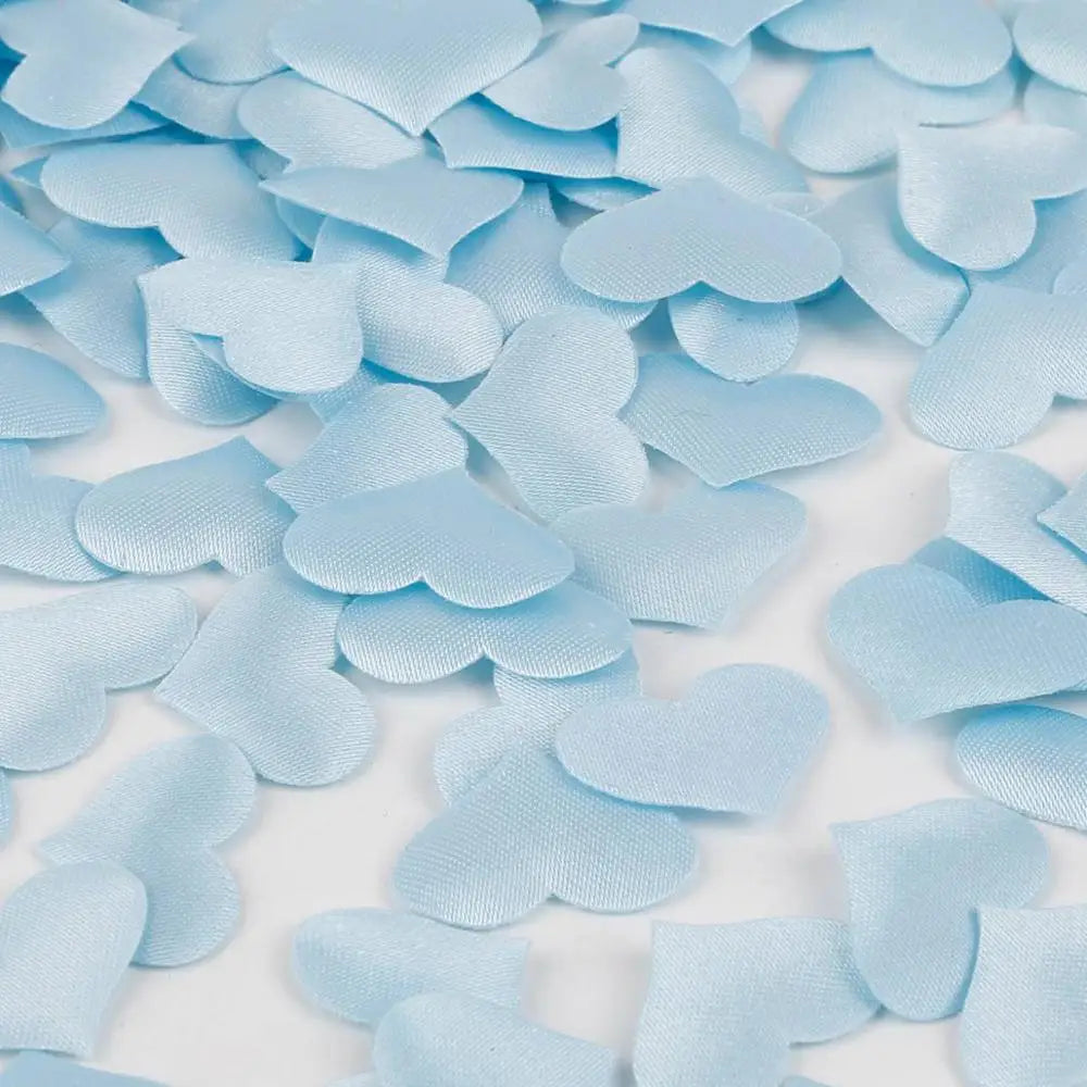Light blue heart-shaped sponge confetti scattered on a white surface.