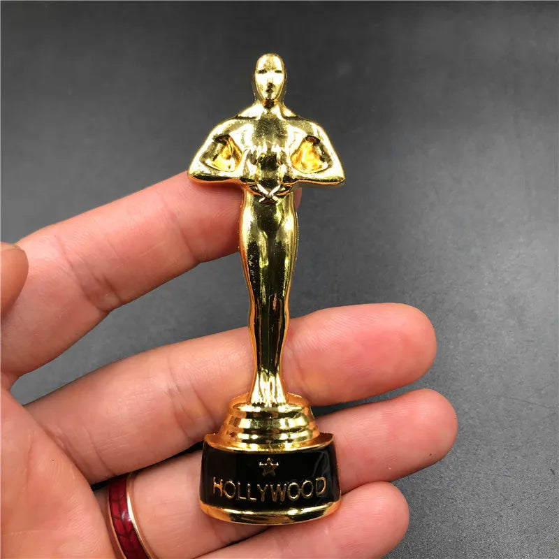 Aimant de réfrigérateur en métal doré, en forme de figurine stylisée, avec le mot HOLLYWOOD sur la base.