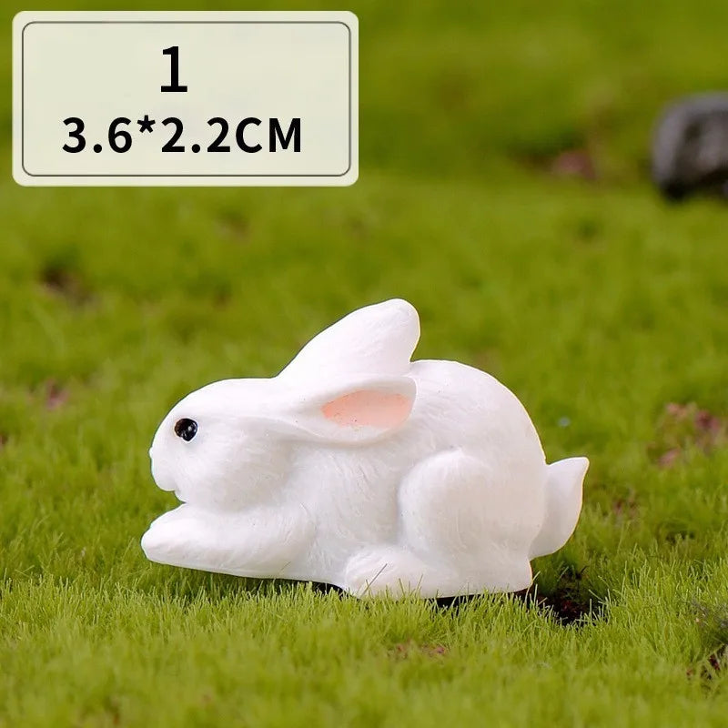A white miniature rabbit figurine lying on green grass.