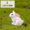 A small white rabbit figurine sitting on green grass.