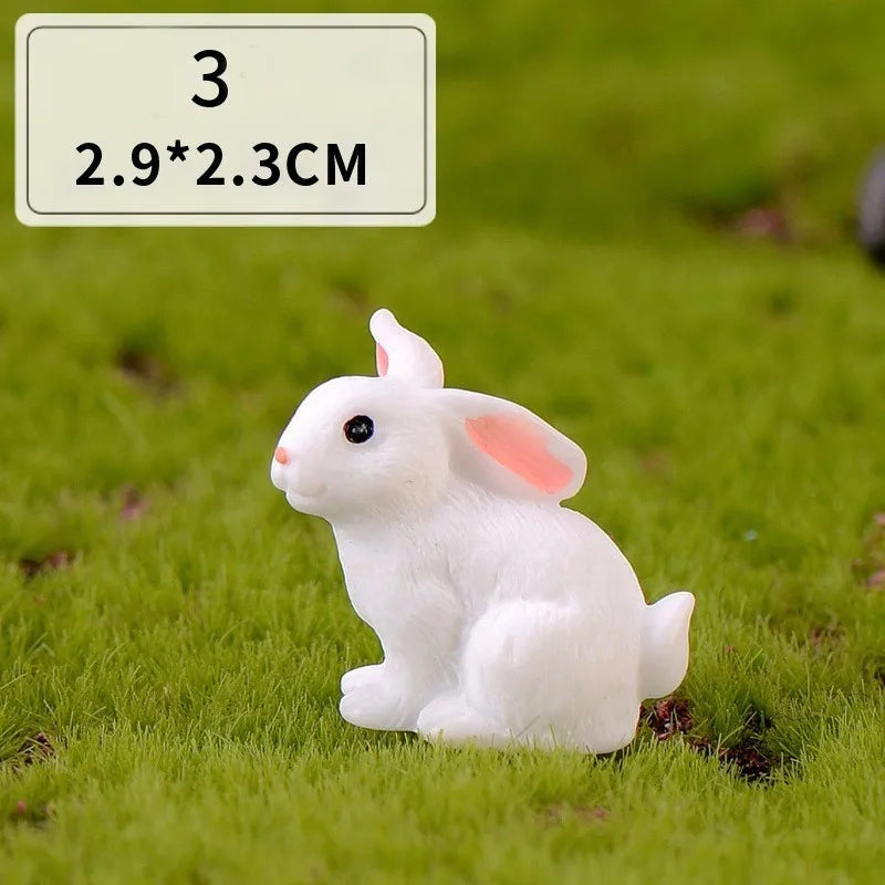 A small white rabbit figurine sitting on green grass.