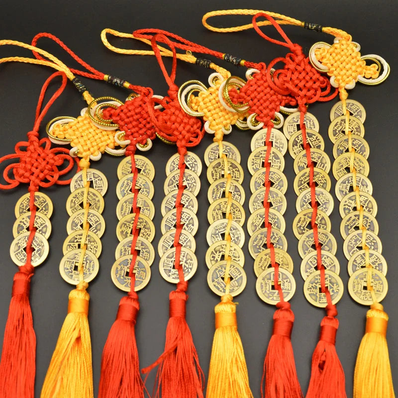 A set of I Ching copper coins with handwoven knots and tassels in red, yellow, and gold.