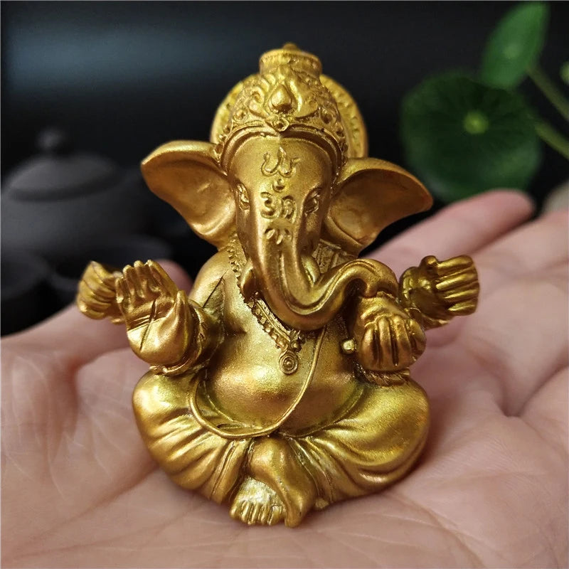 Golden handcrafted statue of Ganesha sitting on a hand
