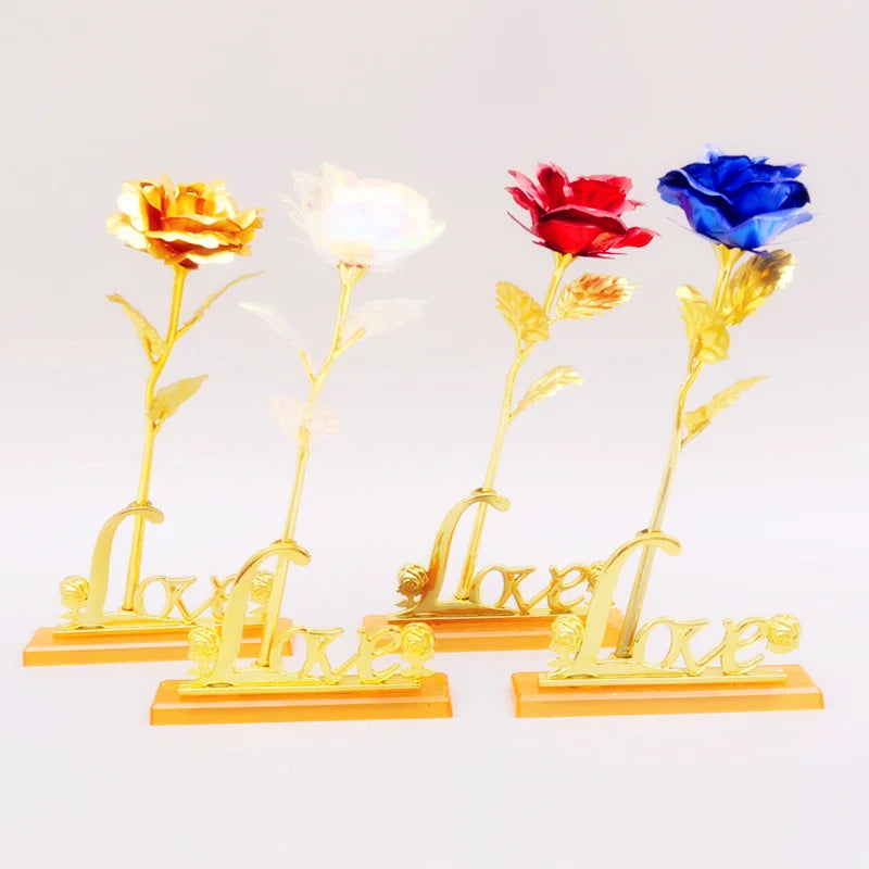 A bouquet of four artificial roses in various colors, including yellow, white, red, and blue, mounted on gold foil lettering.