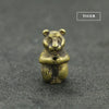 A small brass tiger statue with an incense holder resting on a dark gray surface.