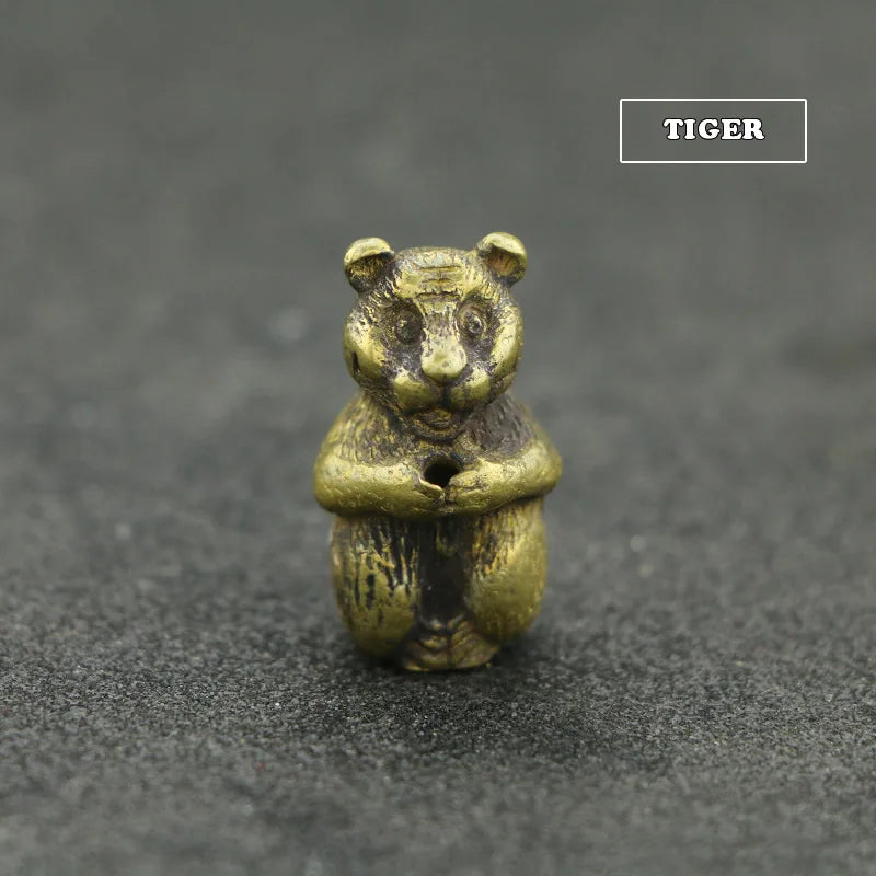A small brass tiger statue with an incense holder resting on a dark gray surface.