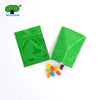 Green foil zip bags containing colorful pills or candies
