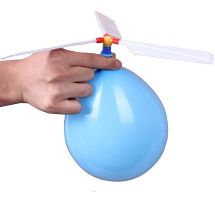 A hand is holding a light blue balloon helicopter toy with white blades.