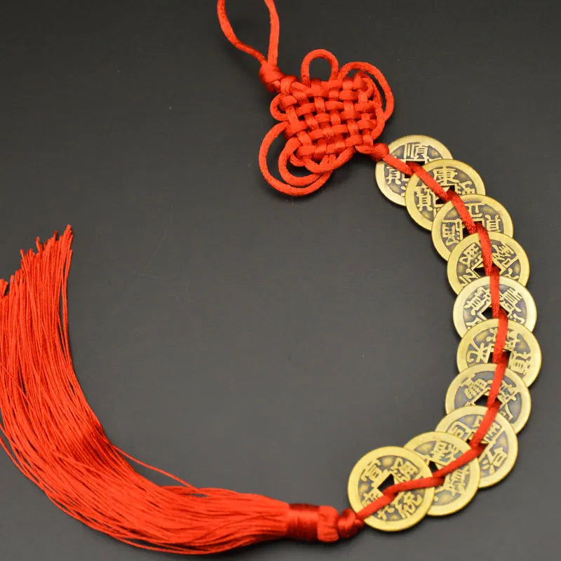 A circular charm made of copper coins and a red thread with a handwoven knot for Feng Shui.