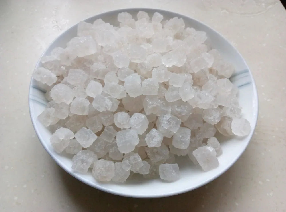 A pile of white natural unrefined sea salt crystals in a white dish.
