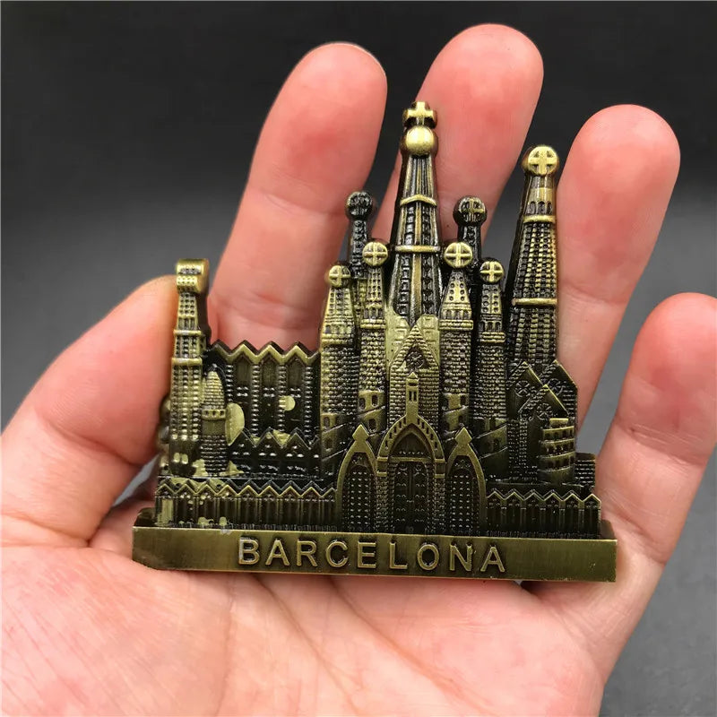 Une main tient un aimant de réfrigérateur décoratif avec le skyline de Barcelone et du texte.