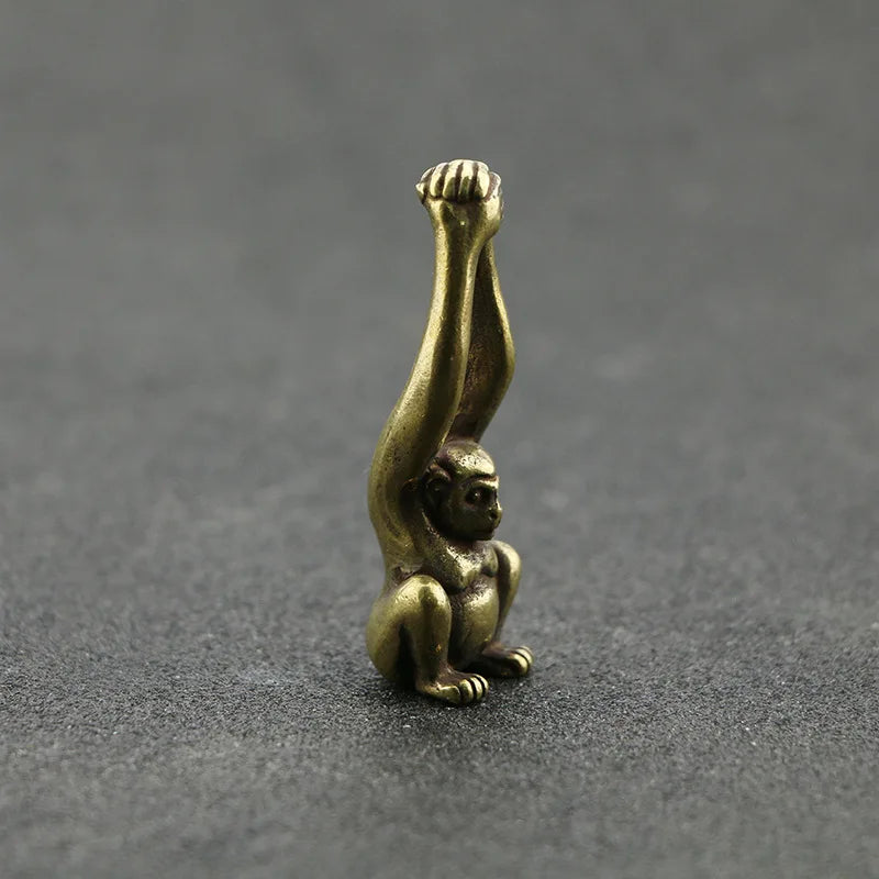 A vintage brass monkey key chain charm sculpted in a grasping pose.