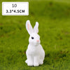 A white miniature rabbit figurine sitting on green grass.