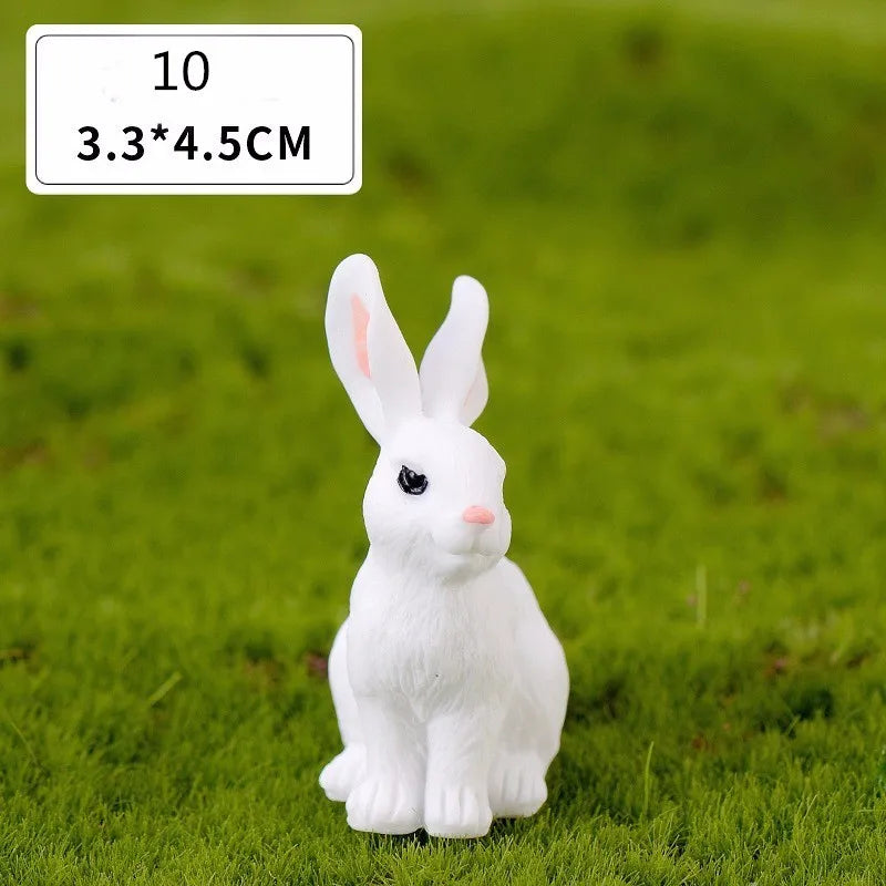 A white miniature rabbit figurine sitting on green grass.