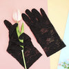 Black sheer lace gloves with a pink tulip flower on a light pink background.