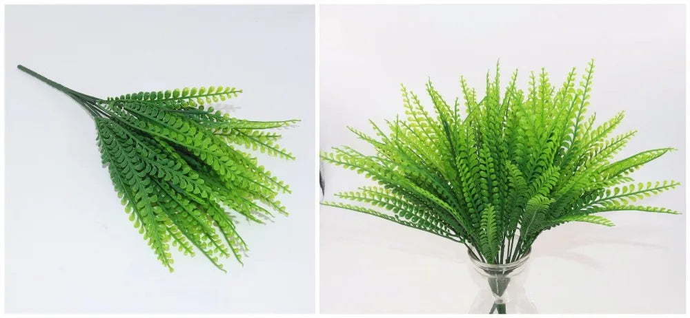 A close-up of bright green artificial fern and leaf sprigs arranged in a glass vase.