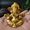 Golden handcrafted statue of Ganesha sitting on a hand