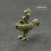 A brass rooster statue with a head and body, standing on a dark gray surface.