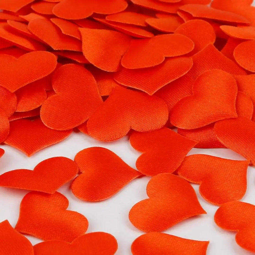 Orange heart-shaped sponge confetti scattered on a white surface for weddings and celebrations
