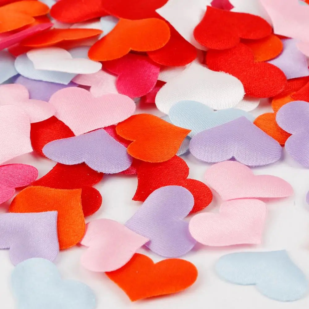 A colorful mix of heart-shaped sponge confetti in shades of red, orange, pink, purple, and blue scattered on a white surface.