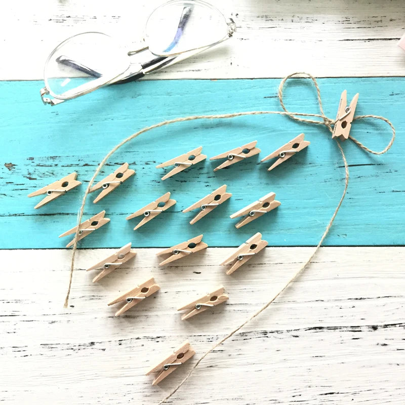 A collection of natural wooden clothespins tied together with twine on a light blue wooden surface.