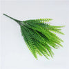 A sprig of bright green artificial fern leaves and fronds.