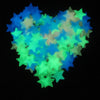 A heart shape made of glow-in-the-dark star stickers in shades of blue and green against a black background.