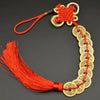A necklace featuring a red silk tassel and a string of round copper coins used as an I Ching Feng Shui charm.