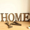 Vintage wooden alphabet letters spelling HOME arranged on a light wooden surface.