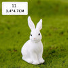 A white miniature rabbit figurine sitting on green grass.
